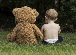 baby with teddy bear on grass