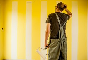 man scratching head with paint roller