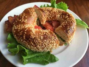 whole wheat bagel with lettuce and bacon on a plate