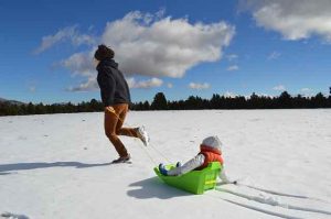 woman in snow with child in sled