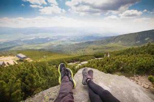 man and woman's feet on a rock overlooking a valley