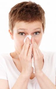 woman with tissue sneezing